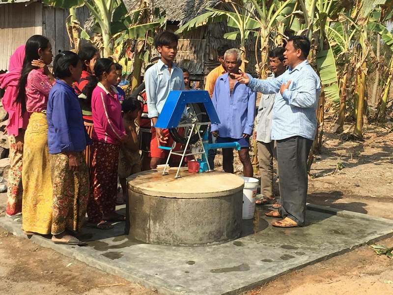 区長さんが井戸の説明をしています。回転式の漕ぎ棒です。なんだか最新式の井戸です。